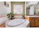 A spa-like bathroom featuring a soaking tub with tile surround and natural light from a glass block window at 12276 Caminita Pl, Las Vegas, NV 89138