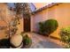 Charming courtyard entrance with decorative plants, a stone path, and a warm, welcoming ambiance at dusk at 12276 Caminita Pl, Las Vegas, NV 89138