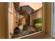 Beautiful private courtyard view through window with water feature and seating area at 12276 Caminita Pl, Las Vegas, NV 89138