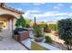 Outdoor kitchen and patio area featuring a grill, dining set, and manicured landscaping at 12276 Caminita Pl, Las Vegas, NV 89138