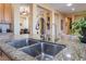 Close-up on a double sink and granite countertop with a view into the adjacent dining and living areas at 12276 Caminita Pl, Las Vegas, NV 89138