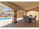 A covered patio overlooking a swimming pool with an outdoor dining set and seating, great for entertaining at 1877 Glory Lily Ct, Las Vegas, NV 89123