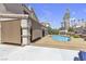 Backyard with a sparkling blue swimming pool, a covered patio, and desert landscaping with palm trees at 1877 Glory Lily Ct, Las Vegas, NV 89123