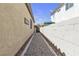 Narrow gravel-filled side yard with white block wall, leading to backyard gate, between two houses at 1877 Glory Lily Ct, Las Vegas, NV 89123