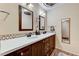 Bathroom with double sinks, white quartz countertop, wood cabinets, and decorative mirrors at 2035 E Warm Springs Rd # 1019, Las Vegas, NV 89119
