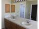 Bathroom with double sinks, tile countertops, and oak cabinets under a large mirror at 2201 E Dandelion St, Pahrump, NV 89048