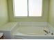 Bathtub under window with tiled deck, neutral fixtures, and tiled backsplash at 2201 E Dandelion St, Pahrump, NV 89048
