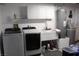 Laundry room with laundry sink, storage cabinets, and modern washer and dryer units at 2201 E Dandelion St, Pahrump, NV 89048