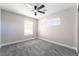 This bedroom features plush gray carpeting, a modern ceiling fan, and bright natural light from two windows at 2625 Cattrack Ave, North Las Vegas, NV 89081