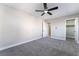 This bedroom provides gray carpet, a ceiling fan, and access to the ensuite bathroom at 2625 Cattrack Ave, North Las Vegas, NV 89081