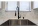 A close-up of the kitchen sink with a black faucet and white quartz countertops at 2625 Cattrack Ave, North Las Vegas, NV 89081