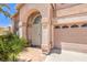 Close-up of the home's entry featuring an arched doorway and gated front porch area with desert landscaping at 2728 Aspen Wood Ave, Henderson, NV 89074