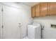 Bright laundry room with white appliances, wood cabinets, and convenient access door at 2728 Aspen Wood Ave, Henderson, NV 89074