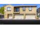 Three-unit tan townhome featuring individual garages and a small balcony on the second level at 3905 Sweet Pine St # 102, Las Vegas, NV 89108