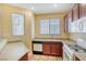 Bright kitchen featuring tile floors, wooden cabinetry, and white appliances, illuminated by natural light from multiple windows at 3905 Sweet Pine St # 102, Las Vegas, NV 89108