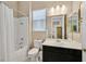 Bright bathroom with a tub shower, toilet, and black vanity with a mirror and sink at 444 Middlestone Ave, Henderson, NV 89011
