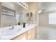 Bathroom with double sinks, light wood cabinets, decorative mirror, and tiled floor at 5031 Droubay Dr, Las Vegas, NV 89122