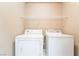 Bright laundry area features a washer, dryer, and a convenient shelf for storage at 5031 Droubay Dr, Las Vegas, NV 89122