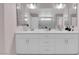 Bathroom vanity featuring double sinks, white cabinets and drawers, and a mirrored backsplash at 5788 Robin Ridge Ave, Las Vegas, NV 89141