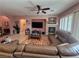 Spacious living room featuring a fireplace, TV, ceiling fan, plantation shutters, and a comfortable sectional sofa at 6009 Arbor Crest St, North Las Vegas, NV 89081
