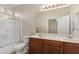 Bright bathroom featuring double sinks, dark wood cabinets, a full mirror, and a shower with glass doors at 6413 White Tiger Ct, Las Vegas, NV 89130