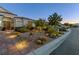 Home's desert landscaping with rocks, cacti, and shrubbery, illuminated by walkway lighting at 6413 White Tiger Ct, Las Vegas, NV 89130