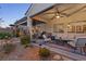 Covered outdoor patio with comfortable seating, a ceiling fan, and view of the landscaped backyard at 6413 White Tiger Ct, Las Vegas, NV 89130