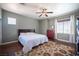 The main bedroom features hardwood floors, a ceiling fan, and a large window with blinds and curtains at 7021 Salt Marsh Ct, Las Vegas, NV 89148