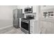 Updated kitchen featuring stainless steel appliances, white cabinets, light countertops, and gray-toned flooring at 7144 Forest Vista St, Las Vegas, NV 89147