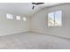 Bright primary bedroom with neutral carpet, ceiling fan and large windows offering views of the neighborhood at 9632 Cherry Canyon Ave, Las Vegas, NV 89129