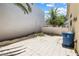 This backyard features a tiled area, white walls, a garbage can, and a tree at 10348 Cherry Brook St, Las Vegas, NV 89183