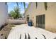 An image of a simple backyard that shows a tiled patio, a house with light yellow walls, and some trees at 10348 Cherry Brook St, Las Vegas, NV 89183