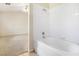 A bathroom featuring a bathtub with shower, with plain white tiles, with a view of an adjacent carpeted room at 10348 Cherry Brook St, Las Vegas, NV 89183