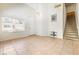 Spacious living room with tile floors, high ceilings, staircase access, and ample natural light from the window at 10348 Cherry Brook St, Las Vegas, NV 89183