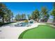 A backyard pool area with mature trees, waterfall feature, and artificial grass at 1106 E Athens Ave, Henderson, NV 89015
