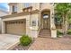 This home's exterior highlights a two-car garage and a welcoming entrance with brick steps and stone accents at 1844 Winners Cup Drive, Las Vegas, NV 89117