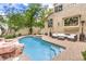 An inviting pool area with rock features, lounge area, and lush landscaping creates a backyard oasis at 1844 Winners Cup Drive, Las Vegas, NV 89117