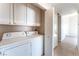 A laundry room includes a washer and dryer with white cabinets for storage at 2111 Hollow Oak Ave, North Las Vegas, NV 89031