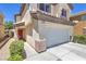 View of the front of the house showcasing a two-car garage, red front door, and landscaping at 261 Fairway Woods Dr, Las Vegas, NV 89148