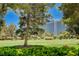 View of the golf course with well-manicured green, mature trees, and community buildings at 2851 Queens Courtyard Dr, Las Vegas, NV 89109