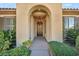 Inviting front entrance with stucco archway, decorative lighting, and lush landscaping enhancing curb appeal at 37 Stonemark Dr, Henderson, NV 89052