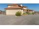 View of the home's exterior featuring multi-car garage, desert landscaping, and a gravel driveway at 3821 Tumbleweed Ave, Pahrump, NV 89048