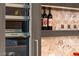 Close up shot of modern bar, featuring custom wine storage, marble backsplash, and ambient lighting at 387 Solitude Peak Ln, Henderson, NV 89012
