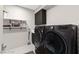 Modern laundry room with gray washer and dryer, open shelving and cabinet space for convenient organization at 387 Solitude Peak Ln, Henderson, NV 89012