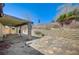 The backyard has a covered patio, a retaining wall, and mature trees, providing a private outdoor space at 5121 Gains Mill St, Las Vegas, NV 89122