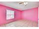 Bright bedroom featuring pink walls, tile floors, ceiling fan, and a window offering natural light at 5121 Gains Mill St, Las Vegas, NV 89122