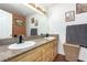 Bathroom featuring double sinks, granite countertop, and framed mirror, with wood laminate flooring at 5424 Geneive Ln # 105, Las Vegas, NV 89108