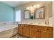 Bathroom features dual sinks, decorative mirrors and tub with a window at 6109 Sandstone Mesa Dr, Las Vegas, NV 89130
