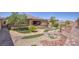 Wide view of the landscaped backyard showcasing artificial turf, mature trees, and a rock water fountain at 6315 Carol Butte Ct, Las Vegas, NV 89141