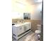 Bathroom with double sinks, white cabinets, tile accent wall, wood floors, and a decorative mirror at 6441 Brushwood Ln, Las Vegas, NV 89107
